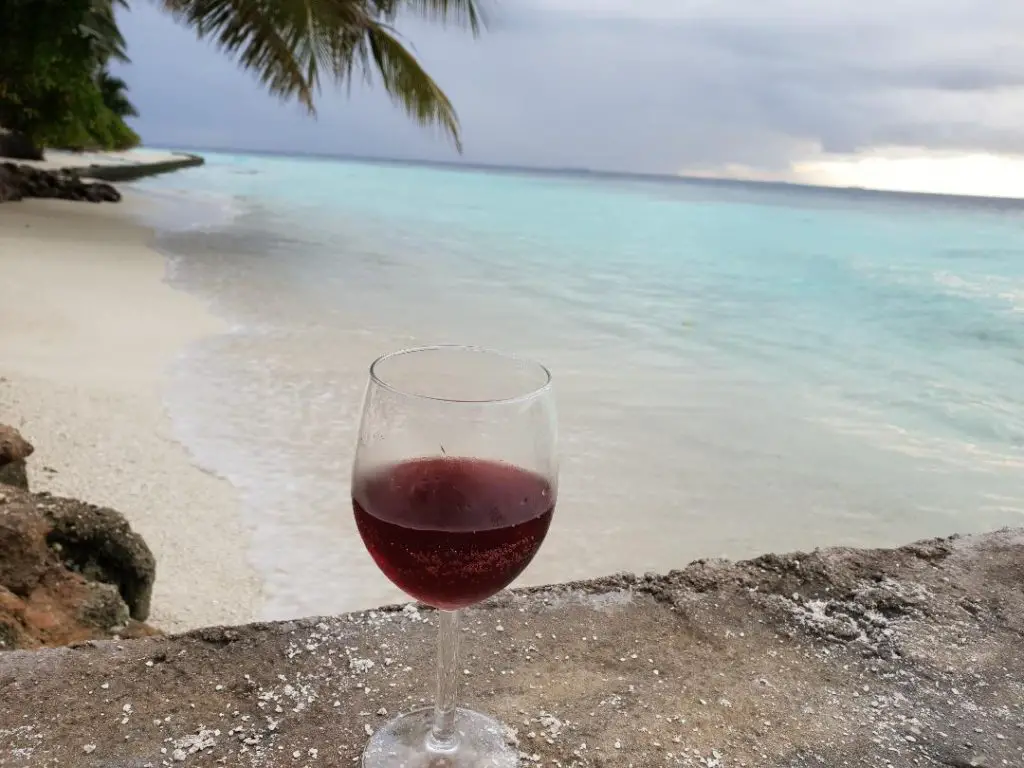 beautiful Maldives beach with wine glass in foreground -first time visit to Maldives