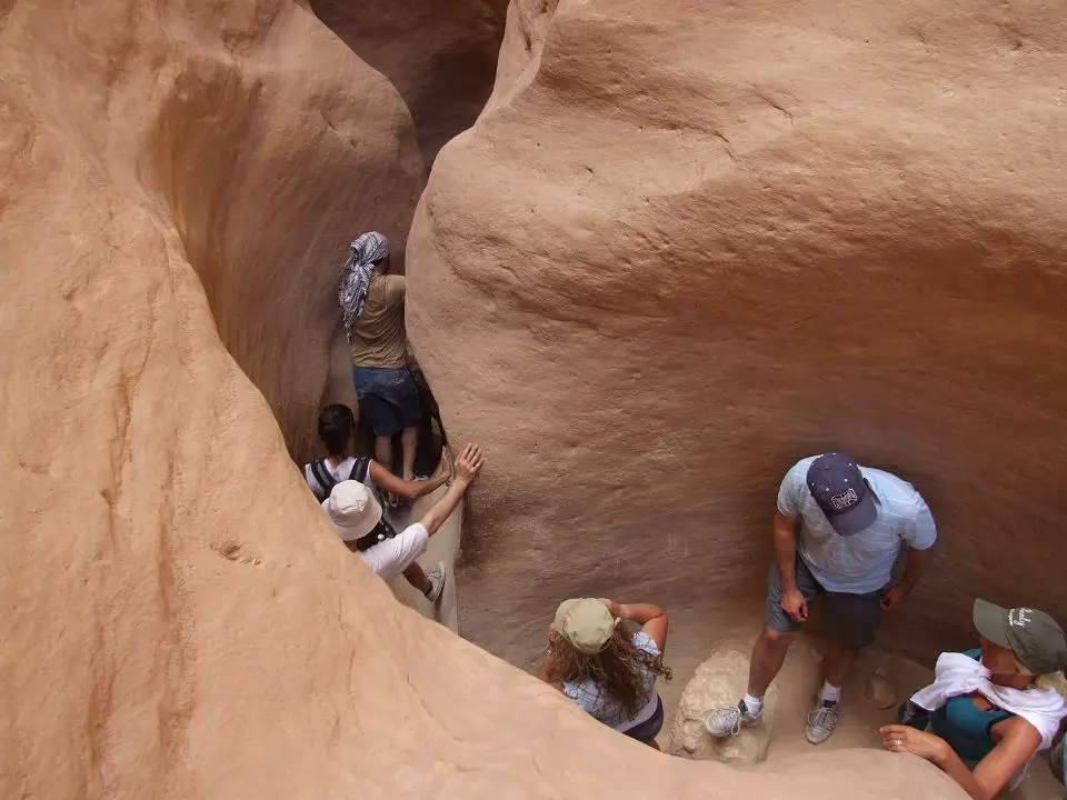 a tight curving canyon shows people below walking though the colored rock canyon- things to do in Egypt