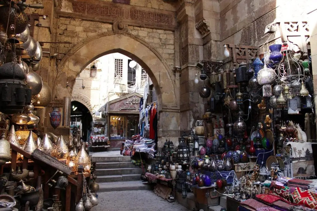 Bazaar in Cairo shows several hangin lamps and an archway carved of stogne