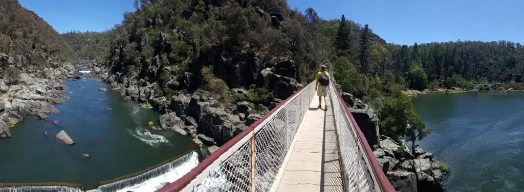 crossing a small pedestrain bridge across a lake. Tasmania itinerary